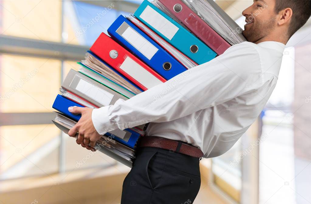 Man with stack of folders with documents on background 