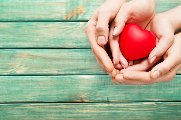 Man and woman holding red heart on background 