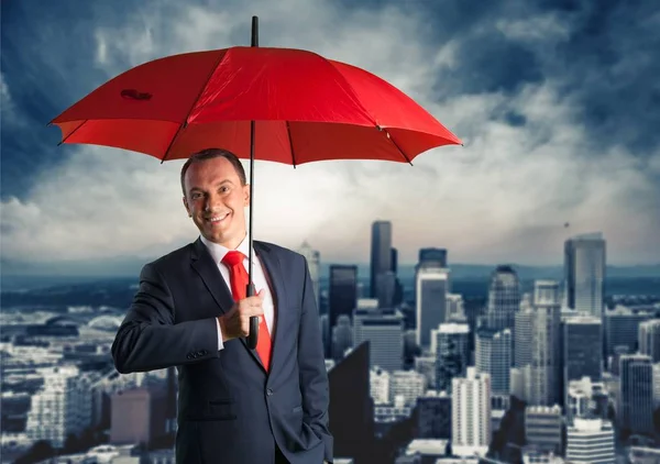 happy businessman under red umbrella,  protection symbol