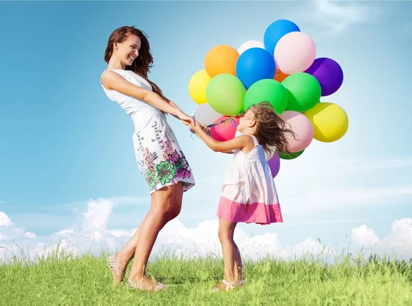 Mor med dotter innehav färgglada ballonger — Stockfoto
