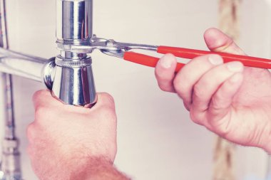 elinde bir tesisatçı ile lavabo ve İngiliz anahtarı.