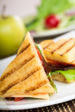 Izgara sandviç beyaz tabakta yarısı