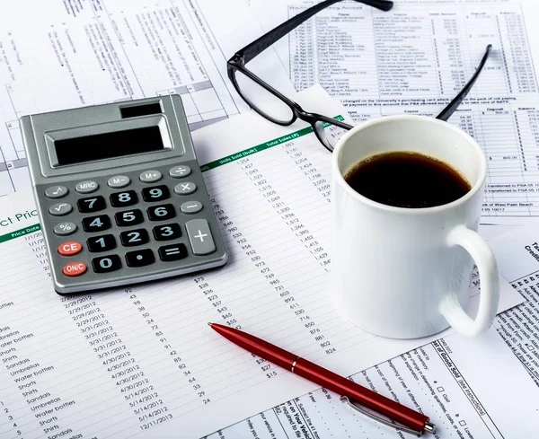 Калькулятор, ручка, очки и кофе на финансовых показателях — стоковое фото