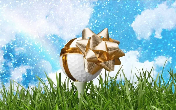 Golf ball on tee with festive ribbon and bow