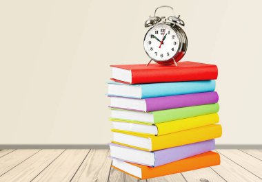 Kitaplar ve çalar saat üzerinde arka izole yığını