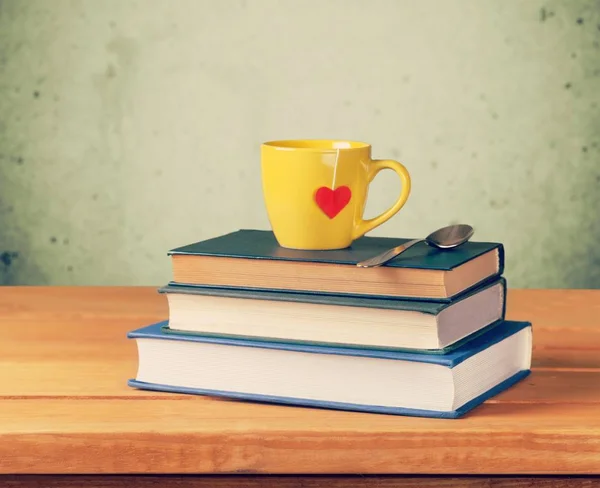 Pile of books with coffee cup on wooden table