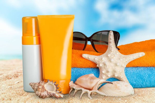 Bottles of sunscreen lotion on beach background
