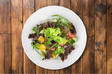 Ahşap arka plan üzerinde beyaz bir tabakta sebze salatası 