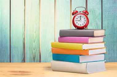 Kitaplar ve çalar saat üzerinde arka izole yığını