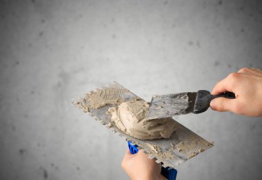 Duvarı alçılayan malayla inşaat işçisi. 