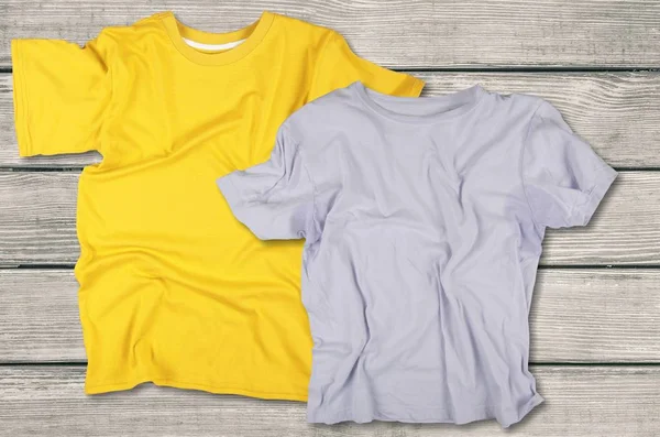 yellow and grey t-shirts on wooden background