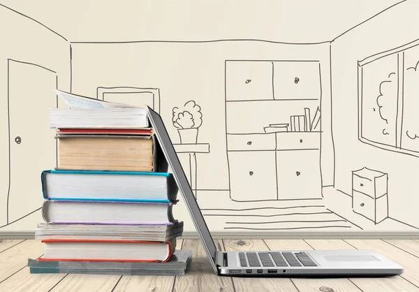 Stack of books with laptop on table