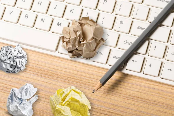 crumpled paper with pencil and computer keyboard