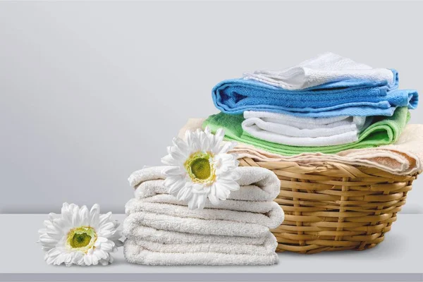 Pile of  fluffy towels with flowers on background