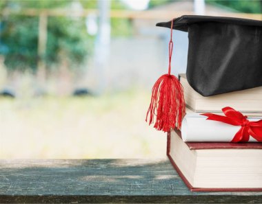 Mezuniyet şapka ve ahşap masa üzerinde kitap yığını