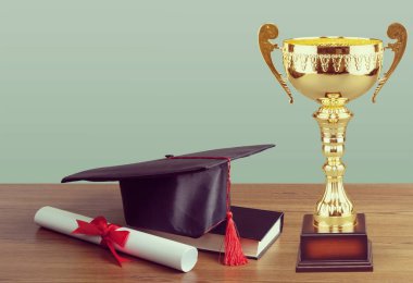 Altın kupa bardak, mezuniyet şapka, kitap ve diploma ahşap tablo