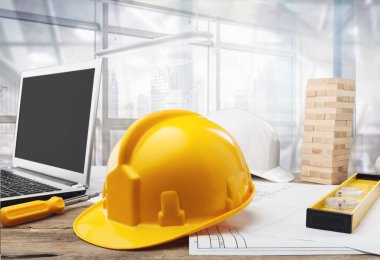 Yellow hard hat, laptop and blueprints, construction concept clipart