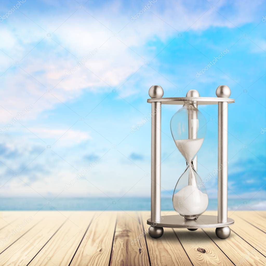 Sand running in hourglass, sea and blue sky 