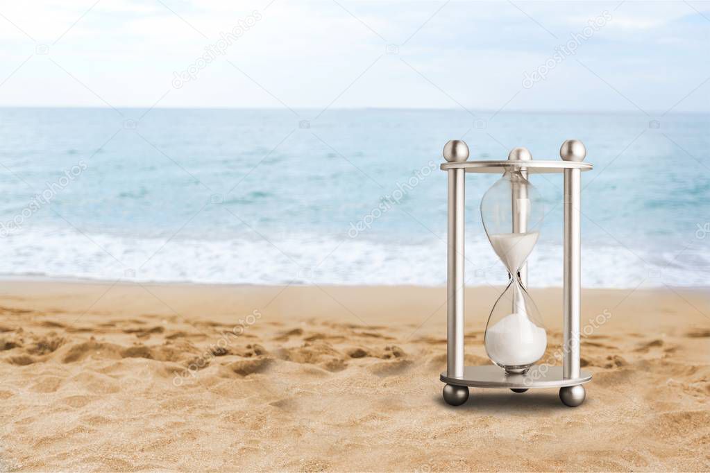Sand running in hourglass on sandy beach 