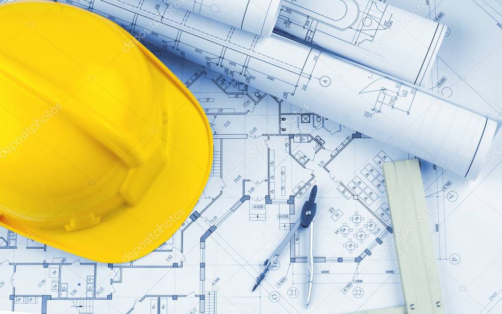 Yellow hard hat and blueprints, construction concept