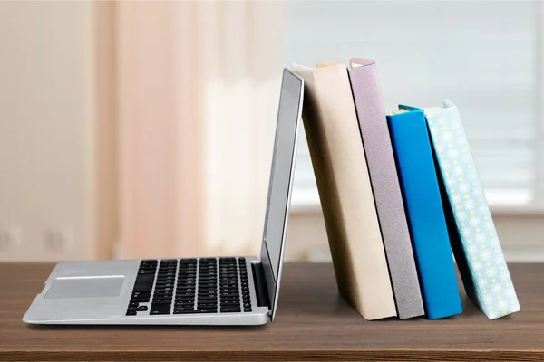 Stack of books with laptop on table