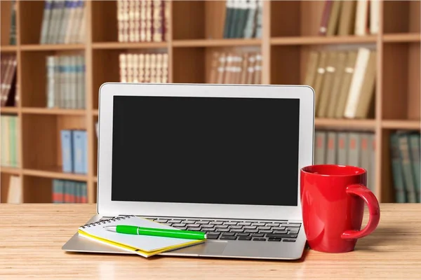 Laptop , pen  and red cup on desk