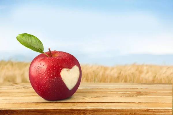 Apple with carved heart sign on light background