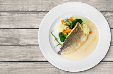 Beyaz tabakta sebzeli ızgara balık.