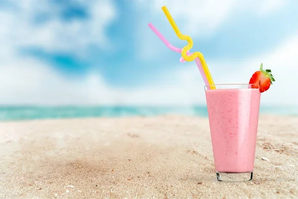 砂のビーチでのイチゴミルクセーキのガラス — ストック写真