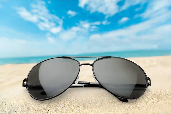 砂の背景に黒のファッションサングラス — ストック写真