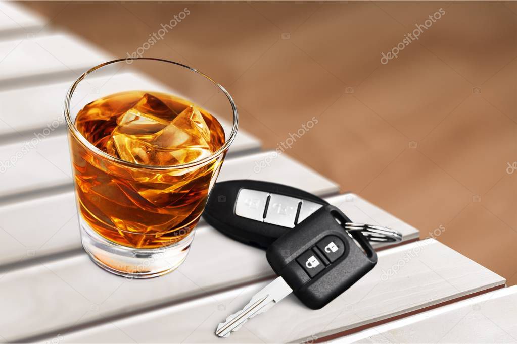 Whiskey with car keys on wooden table