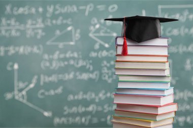 Ahşap masada mezuniyet şapkası ve Kitaplar