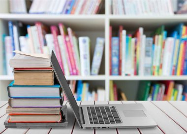 Masada dizüstü bilgisayar ile kitap yığını