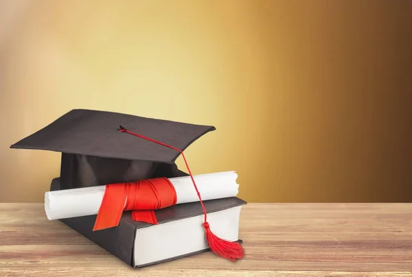 卒業の帽子 本と木製のテーブルに卒業証書 — ストック写真
