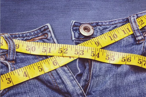 超大牛仔裤和测量带的特写镜头 — 图库照片