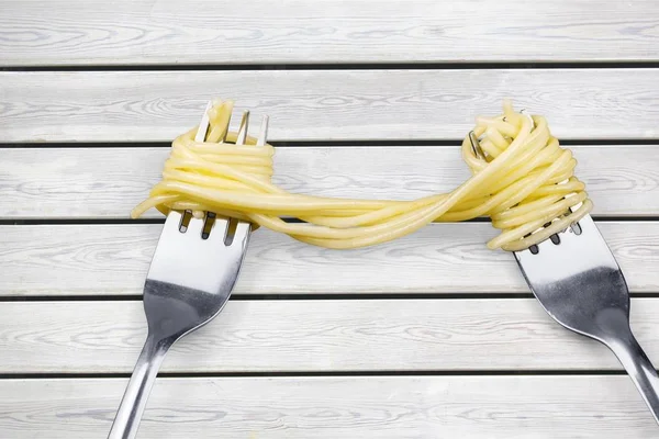 Forks with delicious spaghetti on wooden table
