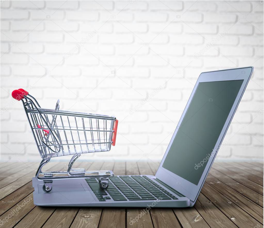 Laptop and shopping cart on wooden table