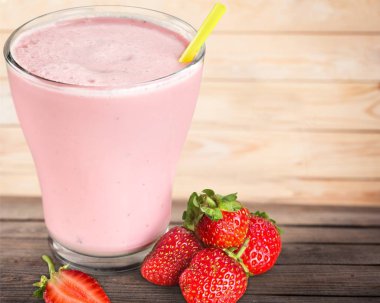 Tahta masada bir bardak taze çilekli smoothie.