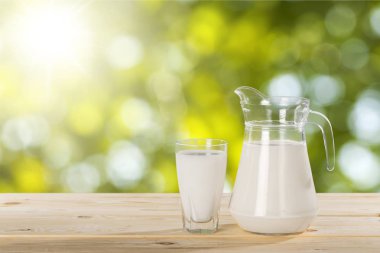 kavanoz ve ahşap masa üzerinde süt ile cam 