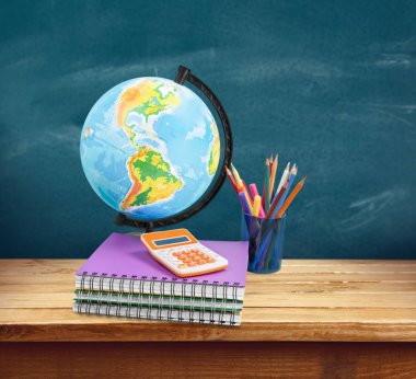 Okul kırtasiye kompozisyona blackboard arka plan, küre, hesap makinesi, defter ve kalemler