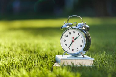 Çim, eğitim ve öğrenme arka planda kitap ve Vintage çalar saat yığını