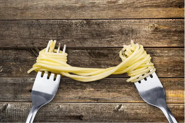 Forks with delicious spaghetti on wooden table