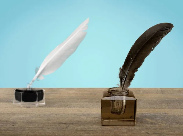 Feather quill pens and glass inkwells on background