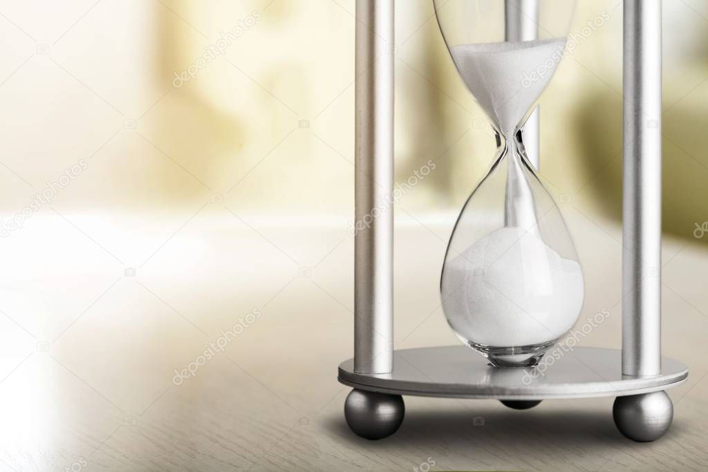 Sand running in hourglass, light background