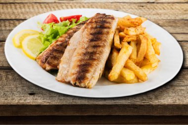 Beyaz tabakta sebzeli ızgara balık.