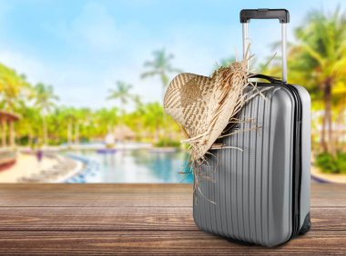 Hasır şapka üzerinde arka izole bavulla 