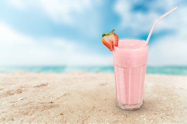Kumlu plajda çilek milkshake bir bardak