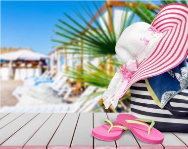 parmak arası terlik, şapka ve arka planda plaj çantası 