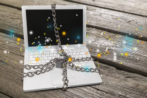 Heavy chain with a padlock around a laptop isolated on background