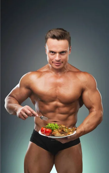 sporty muscular man with meat and vegetables